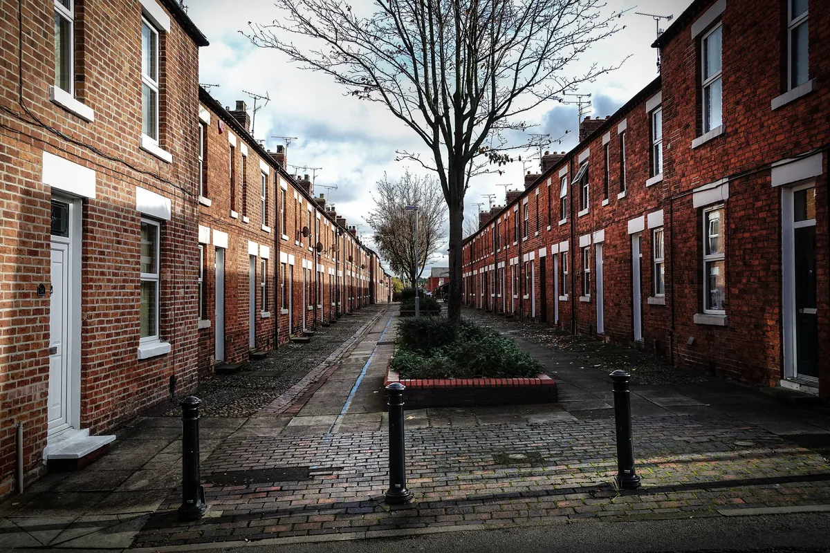 Two rows of red-brick terraced houses facing each other across a paved street in Eastwood