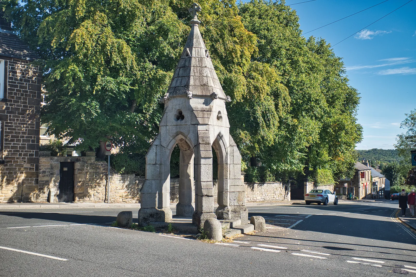 The stone Peel Monument at a road junction in Dronfield, with trees behind